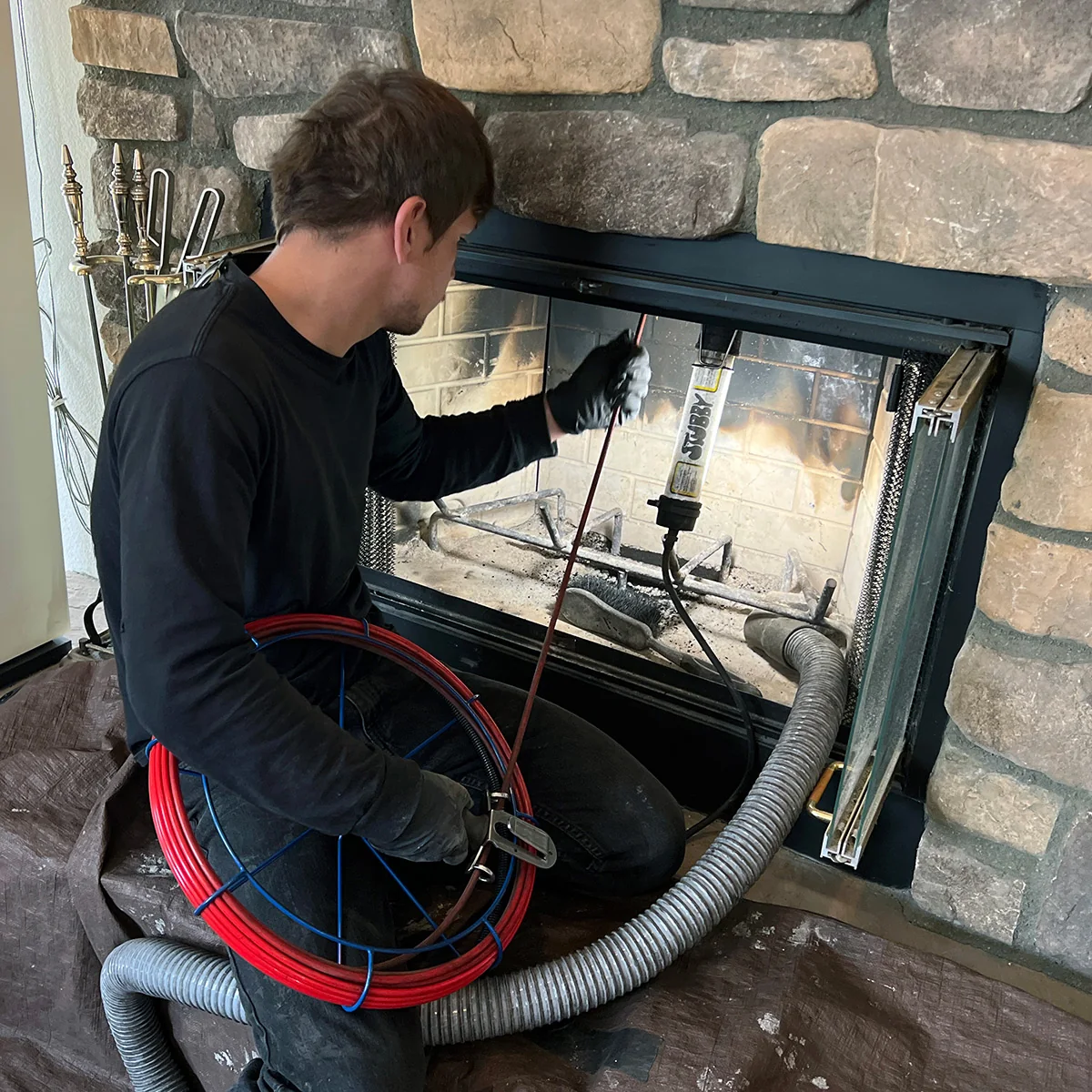 Technician using inspection equipment inside a stone residential fireplace
