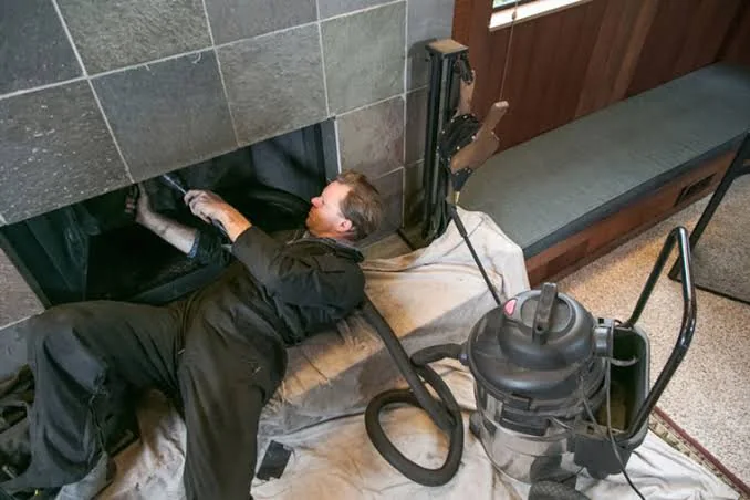 Chimney professional vacuuming and cleaning an accessible fireplace opening